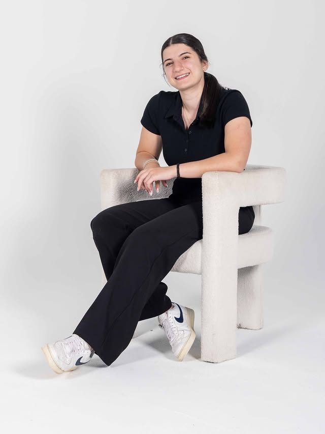 Georgia smiling in a white armchair