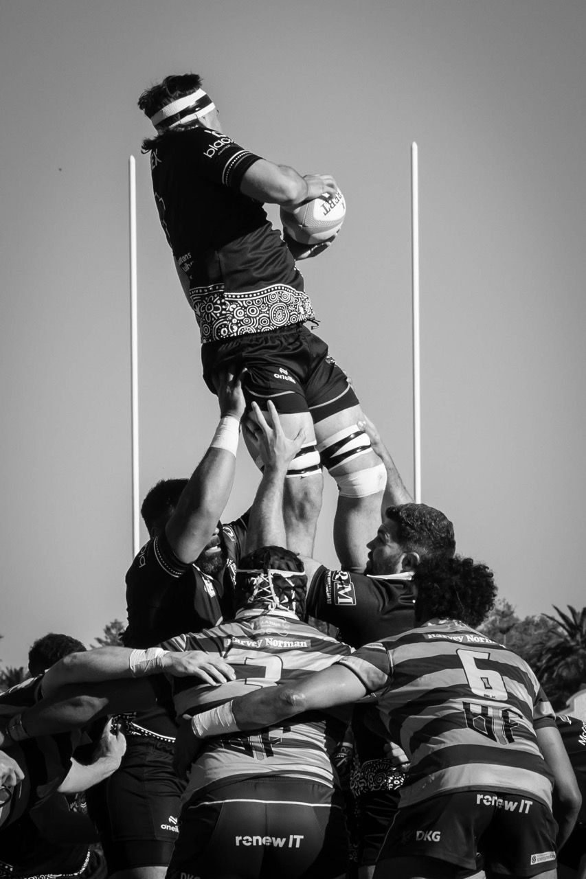 A jumper is lifted high in a lineout between the posts