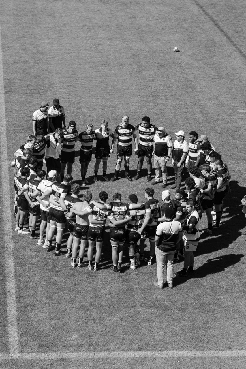 The team stands in a wide circle in the middle of the field