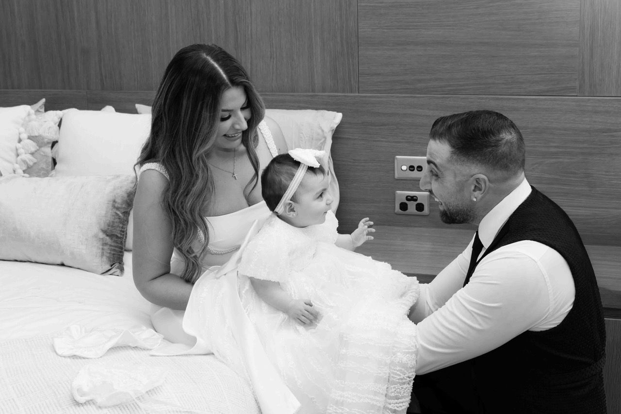 Parents play with their baby on a bed before the service