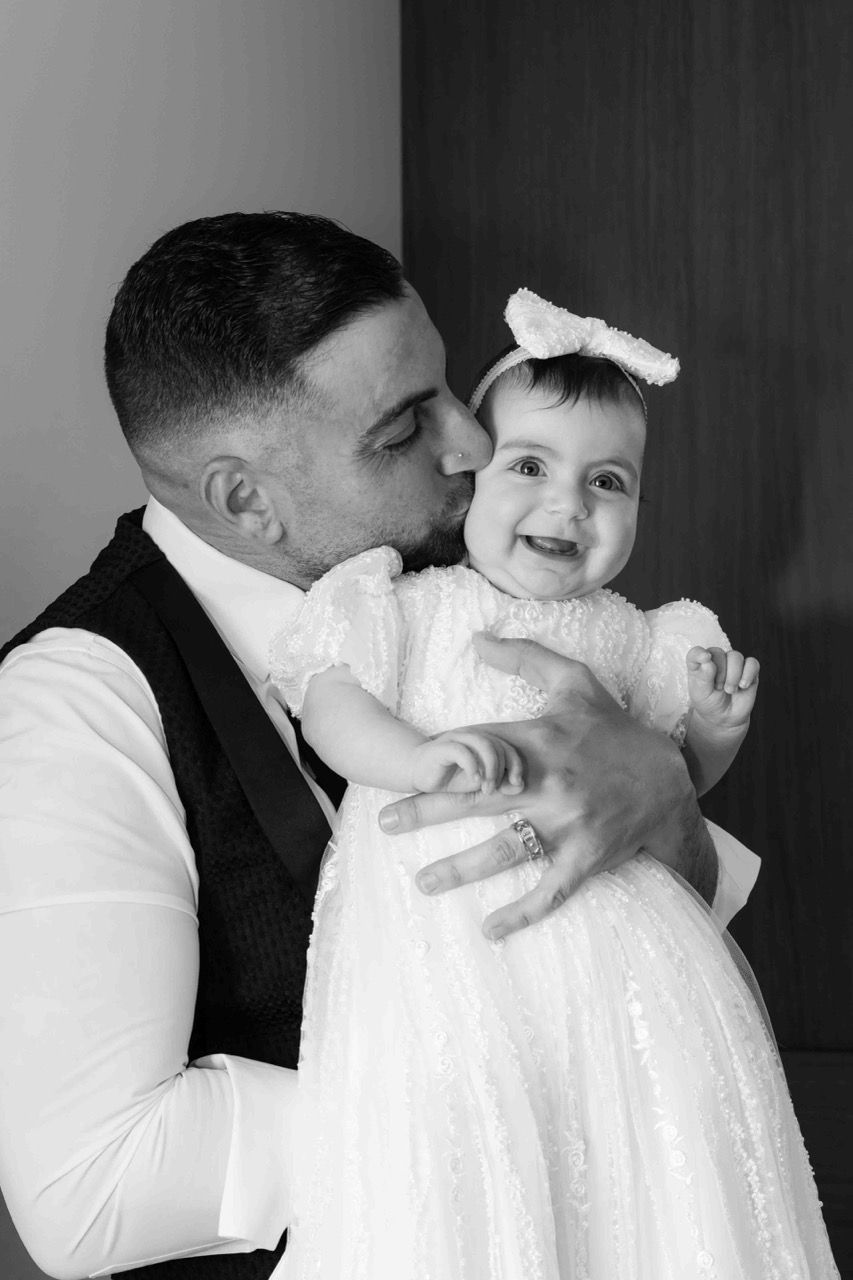 A dad kisses his smiling baby girl