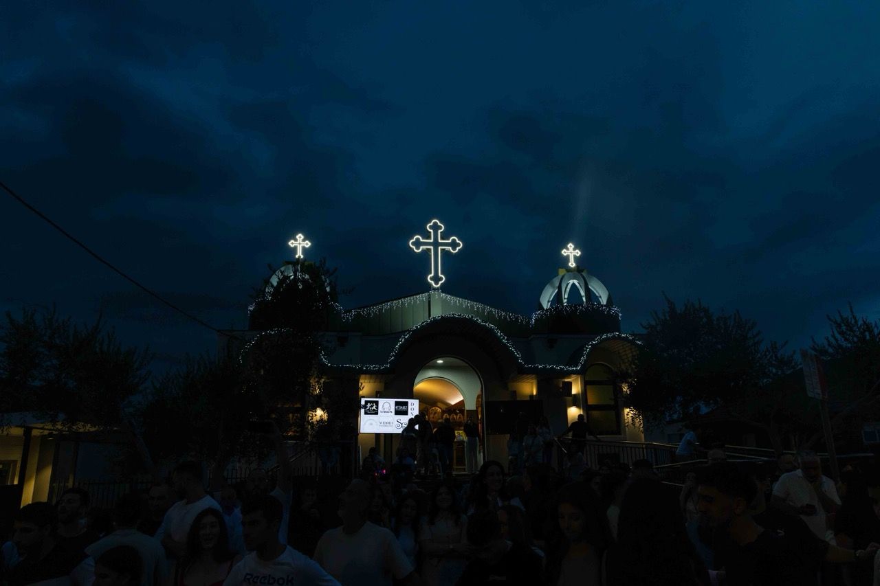A church lit up at dusk above the crowd