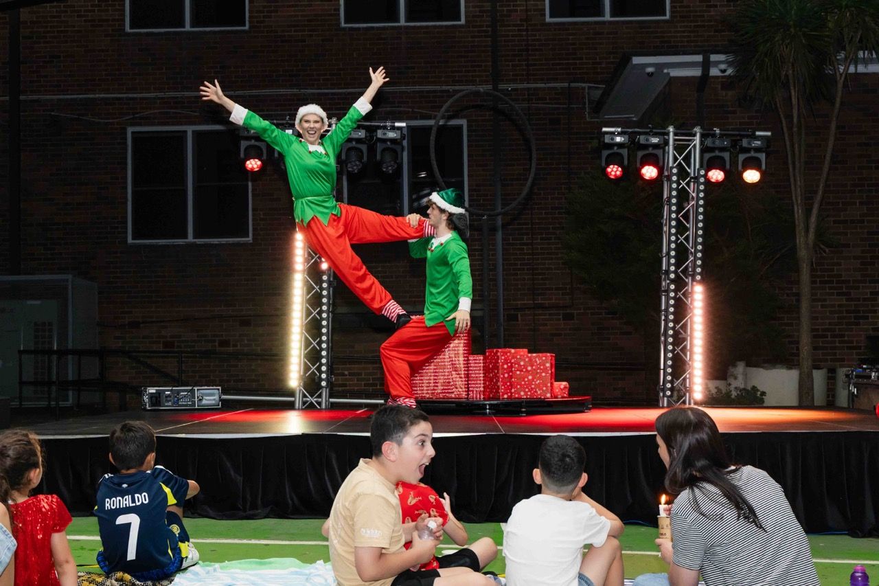 Elves dance on stage in front of seated children