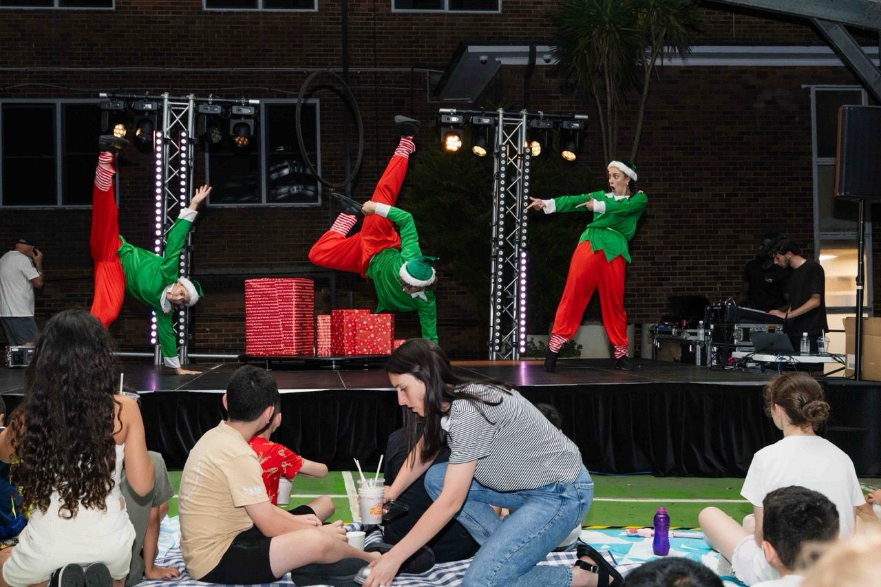 Elves flip and dance on stage at a carols night