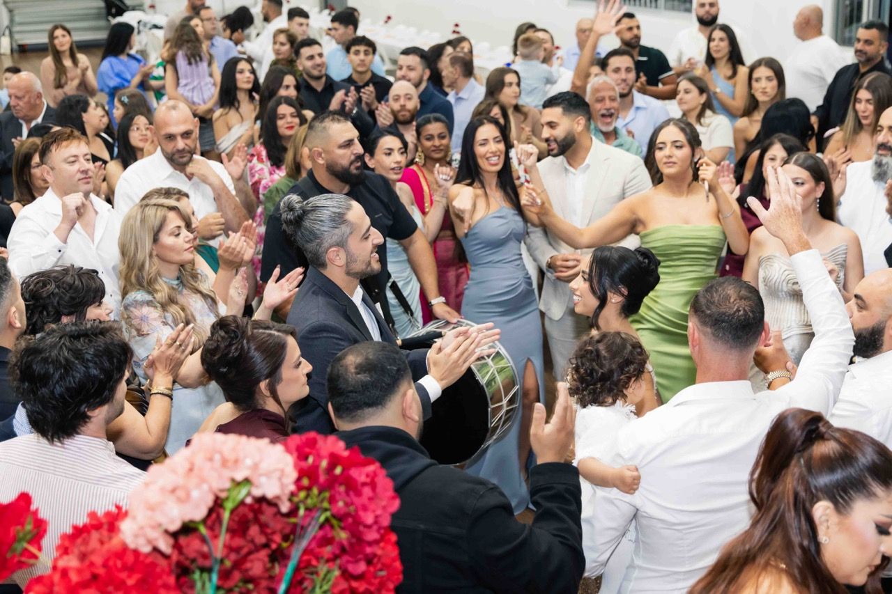 Guests dance and clap around the couple on a packed floor