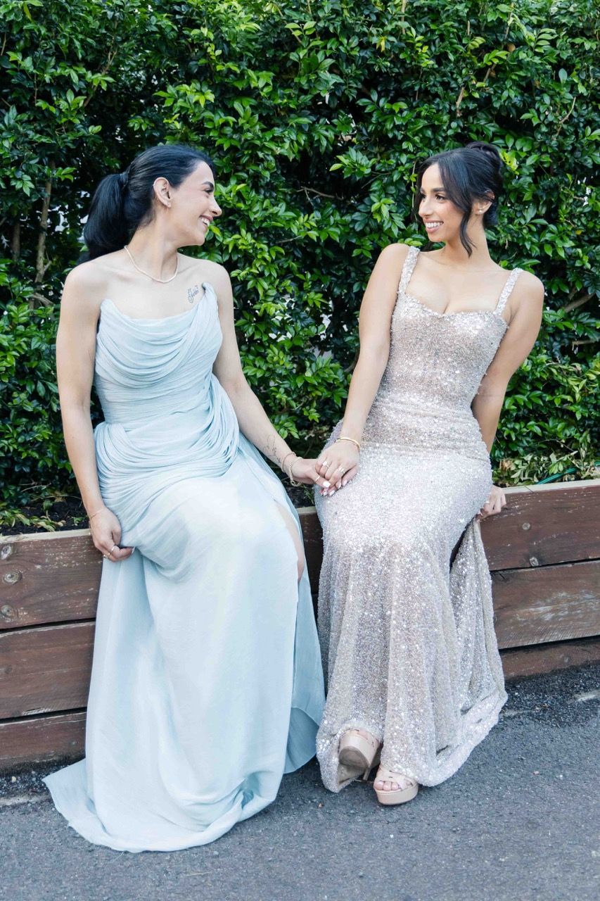 Two friends sit and laugh together on a garden ledge