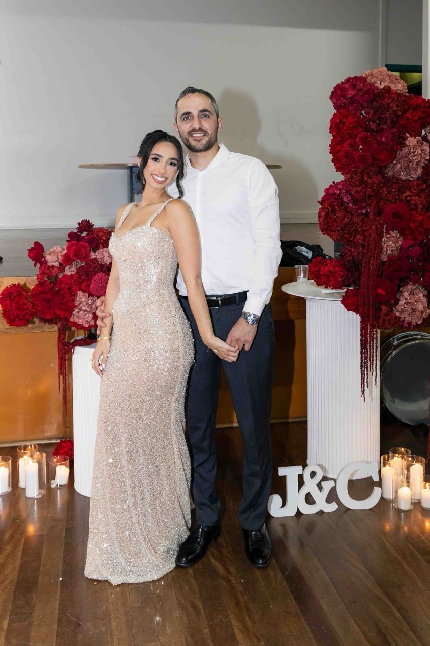 The couple stand together beside the roses and candles