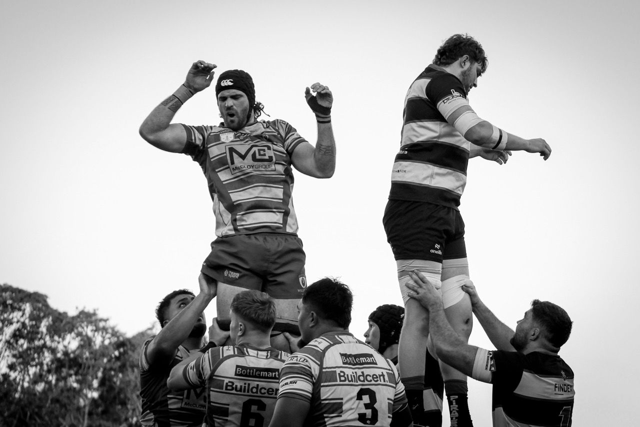 Two lineout jumpers lifted high against a pale sky