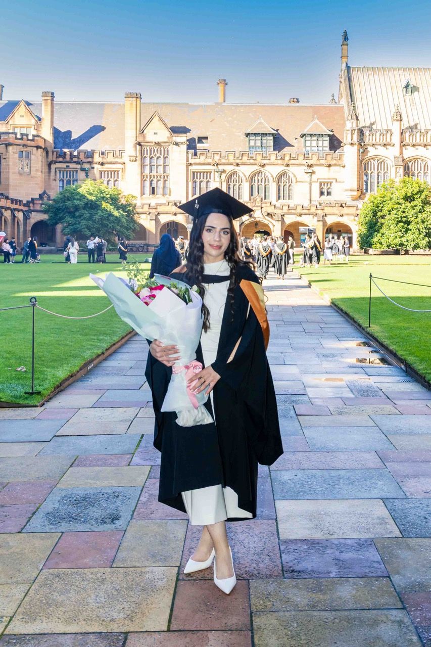 A graduate holds flowers on the path through the quad