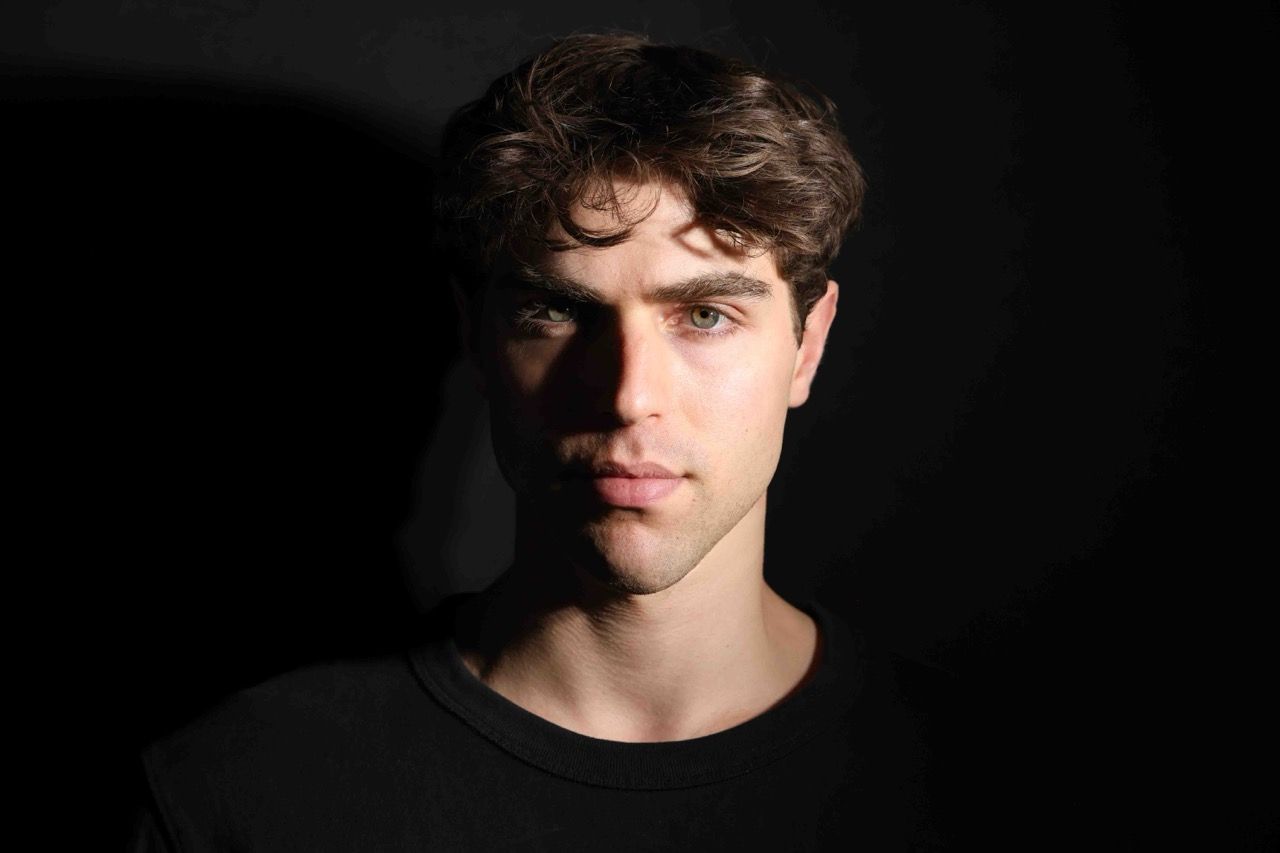 A studio portrait lit from one side against a dark background